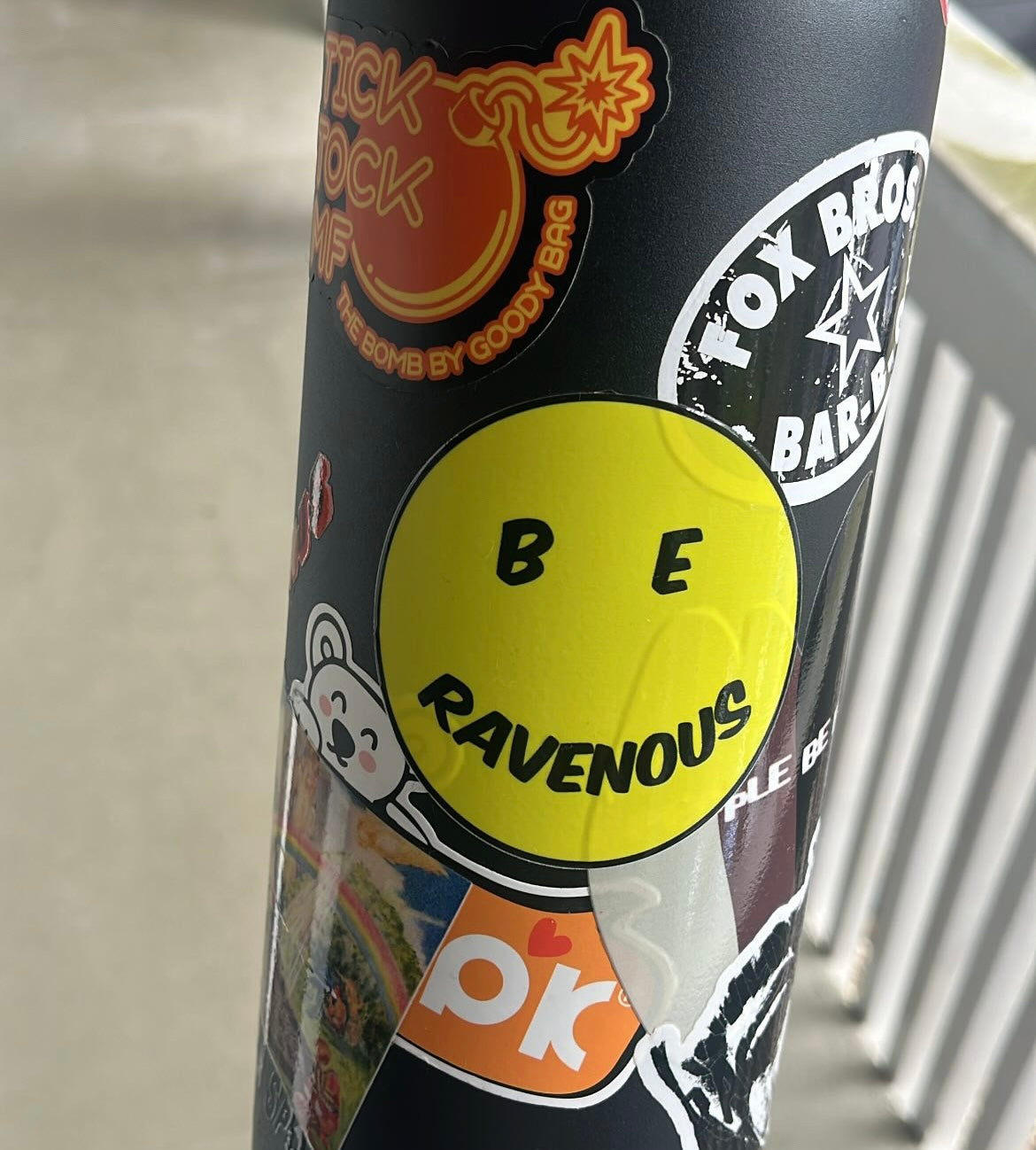 Black canister with colorful stickers, including a yellow one with 'BE RAVENOUS' text.